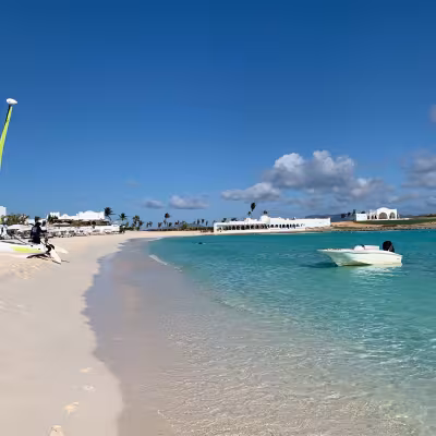 crystal clear beach with blue water and white sand and boats in Anguilla