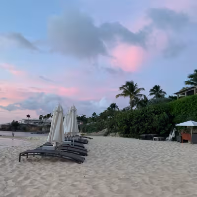 Sunset beach at Belmond Cap Juluca in Anguilla with lounge chairs and palm trees