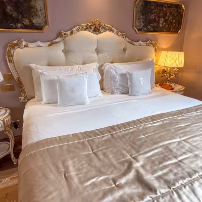 Ornate luxury hotel bedroom with gilded headboard and silk bedding on Lake Como