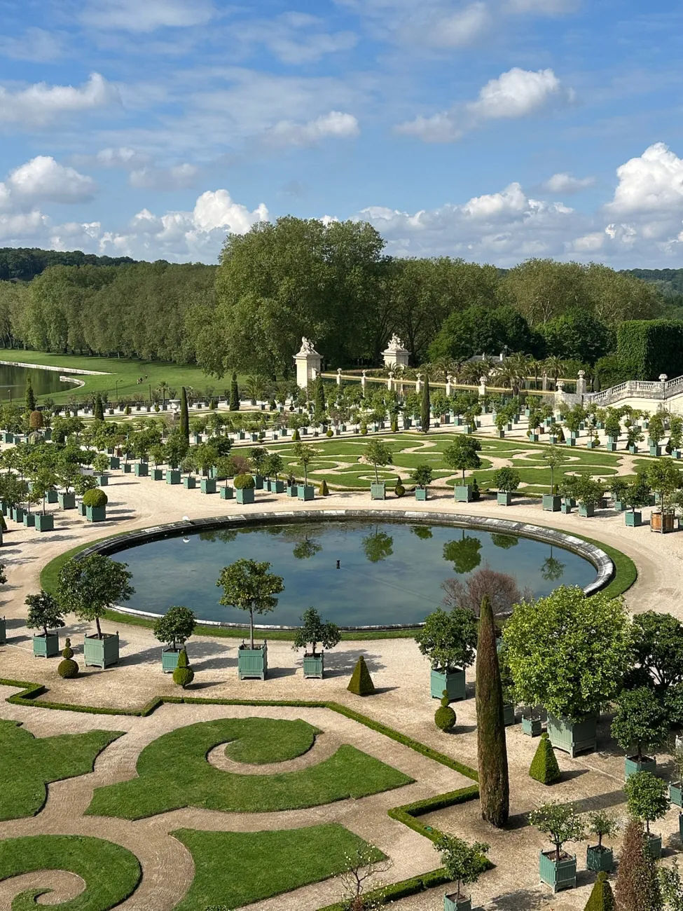 Formal gardens and circular reflecting pool at the Palace of Versailles on a sunny day