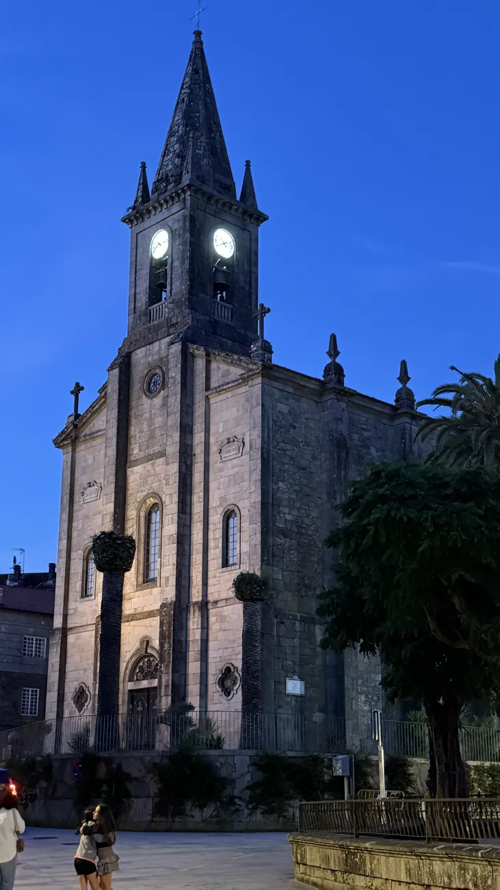 Illuminated church tower at blue hour in a Galician town square